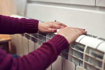 Woman heating on a chilly winter day, energy and gas crisis, cold room, heating problems.