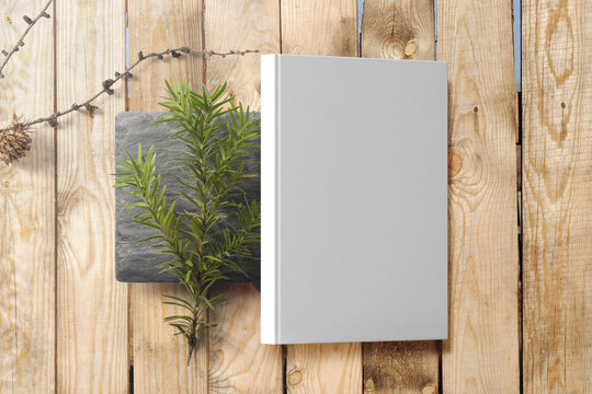 Clean minimal photo book 5.5x8.5 mockup on black stone with plant and stick