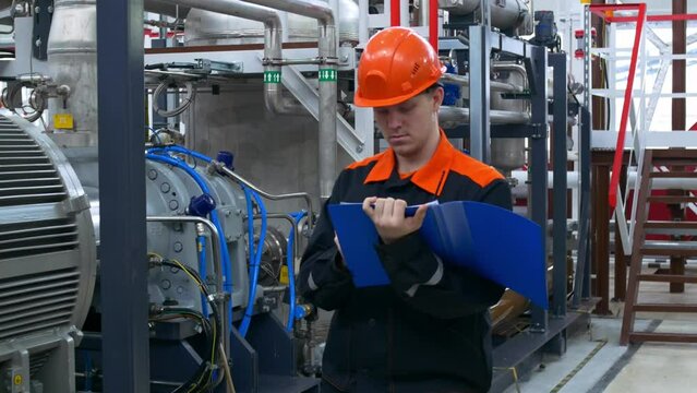 An industrial engineer at his workplace makes a tour of the equipment and records the parameters and comments in the operation of the equipment. The factory worker takes notes.