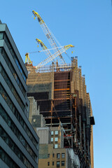 High-rise construction tower crane against the backdrop of a beautiful blue sky. City construction. High-quality photo