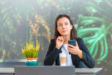 Portrait of young business woman use smartphone at cafe outdoors. Beautiful girl use online...