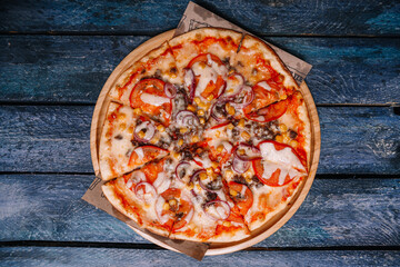 Pizza with corn, onions and tomatoes on a background of boards top view