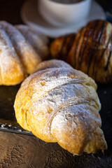 different croissants on a black plate with coffee