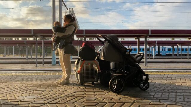Family with little child traveling by train, woman with baby and luggage on Simferopol railway station platform waiting for arrival of the train.