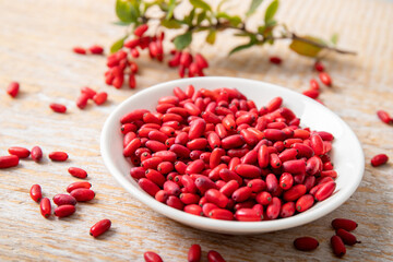 Pile of Berberis vulgaris also known as common barberry, European barberry or barberry on plate in home kicthen. Edible herbal medicinal fruit plant.