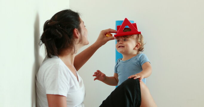 Authentic cute mother and one year old baby child interaction. Candid casual real life mom playing with infant at home indoors