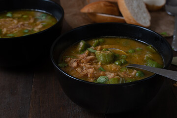 Vegan lentil, okra and peas soup, topped with crispy onions, served in black bowls