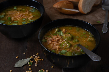 Vegan lentil, okra and peas soup, topped with crispy onions, served in black bowls