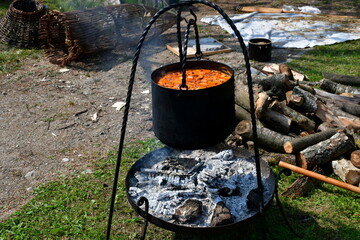 A close up on a pot with goulash or stew boiling after being cooked on a temporary metal grill with...