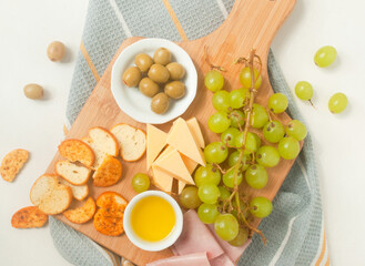 ingredients for a charcuterie board on a wood cutter and a kitchen towel