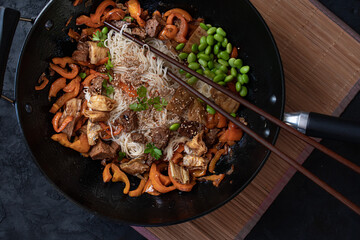 Vegan Stir Fry with yuba, seitan, bell pepper, edamame. .Wheat noodles, served in wok