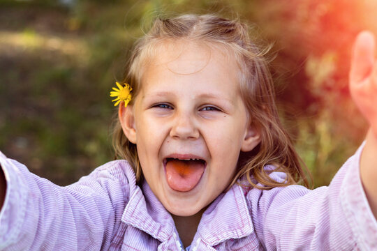 Smiling little girl in the park. Copy space. Happy child looking at the camera. Portrait of a laughing kid outside. Take a selfie