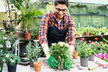 Happy Hispanic woman working in plants and flowers garden shop