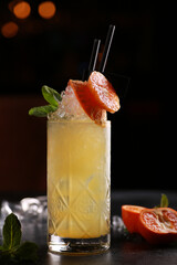 Drinks and cocktails. Yellow beverage with tangerine, orange, mint and ice in a glass on a black table. Bar menu. Background image, copy space
