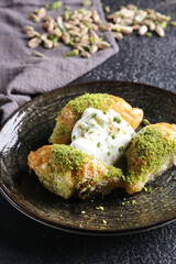Oriental sweets. Pahlava with ice cream nuts, pistachio in a large dish on a black table. Turkish dessert. Background image, copy space, horizontal