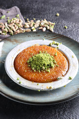 Oriental sweets. Pahlava with nuts, pistachio in a large dish on a black table. Turkish dessert. Background image, copy space, horizontal