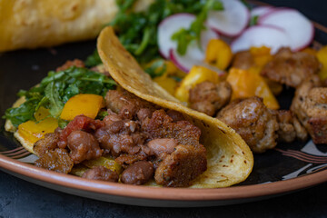 Vegan taco bowl consisting of roasted seitan, bell pepper, salad, refried beans