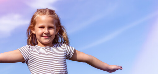 Child on the background of the sky. The concept of lightness and freedom. Happy childhood. Copy space. Banner