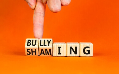 Shaming and bullying symbol. Concept words Shaming and Bullying on wooden cubes. Businessman hand....