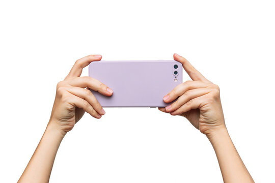 Mobile phone with photo camera in a lilac case in female hands isolated on a white background. Blank with an empty copy space for the design. Mockup of a smartphone. A young woman takes picture