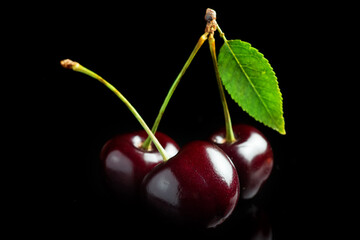 Sweet cherries with cherry leaf on a black background.