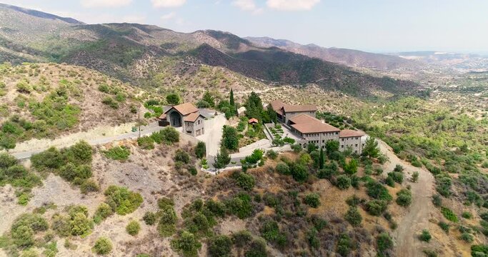 Aerial drone footage of Holy monastery of Panagia Amirous in Apsiou, Limassol, Cyprus. 360 view of the religious stone church, ceramic roof tiles and surrounding mountain landscape from above