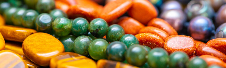 Beads and necklaces made of colored semi precious stones. Background from a variety of beautiful jewelry, multi-colored turquoise stones, amber, cat's eye, pearls.