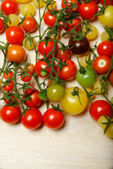 Little red, yellow, green and black cherry tomatoes on white table, nature background, pattern.