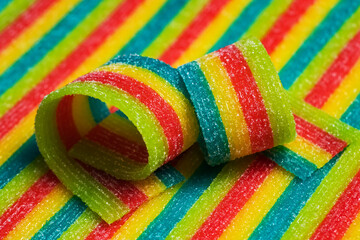 Colorful jelly candies strips in sugar sprinkles. Sour flavored rainbow candy background.