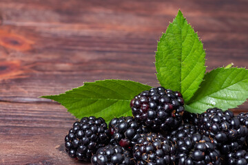 Blackberries with leaves on wooden background close up