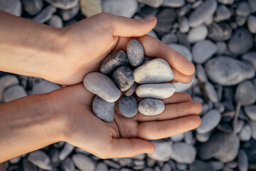 Fototapeta na wymiar girls holding grey smooth pebbles at the beach. High quality photo
