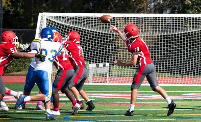 Football quarterback passing the ball over his lineman - obrazy, fototapety, plakaty