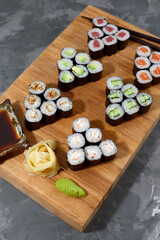 Different types of delicious and juicy sushi and rolls on a wooden board