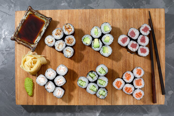 Different types of delicious and juicy sushi and rolls on a wooden board