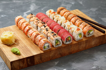 Top view background with set of colorful different kinds of sushi rolls placed on wooden board