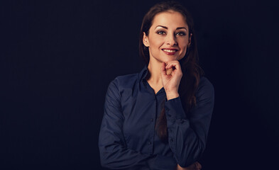 Beautiful thinking  smiling business woman with folded arms in blue shirt on black background with empty copy space for text. Closeup