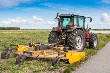 Wheel tractor with lawn mower by the road - obrazy, fototapety, plakaty