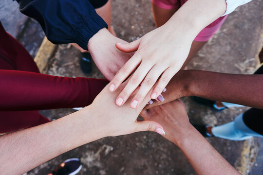 Crop unrecognizable multiethnic friends stacking hands in park