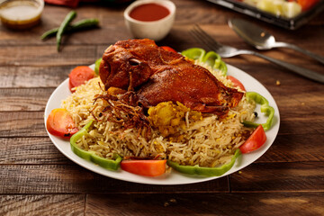 Madhbi chicken or chicken biryani with tomato sauce and salad served in a dish isolated on wooden table background side view of fastfood
