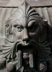 Fototapeta na wymiar Demonic statue face made of metal on a street lamp
