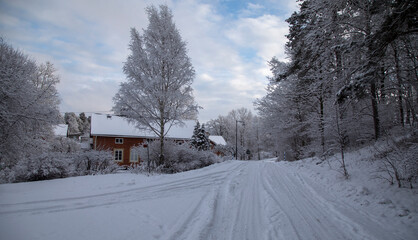 Fototapeta na wymiar Snow covered road and red brick house in winter village
