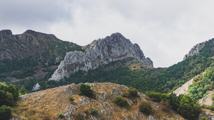 Rocky peak in the mountains with the shape of a tail in a cloudy day