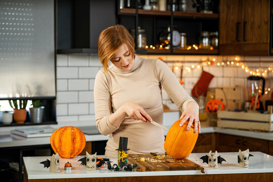 Young woman carving a pumpkin, preparing it for the Halloween holiday, making jack-o-lantern