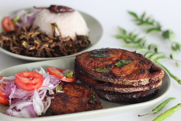 Crispy Surmai fish fry served with white rice meal along with fried bitter gourd and onion tomato salad called challas. Prepared by shallow frying king fish in Kerala style