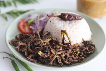 White rice meal along with fried bitter gourd and onion tomato salad called challas served with Sambar.