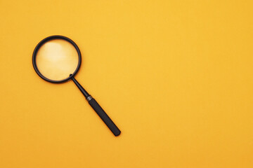 Loupe or magnifying glass on an orange background. Shallow depth of field