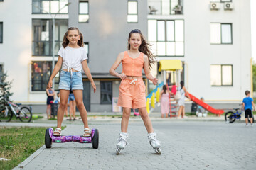 Happy children riding on hoverboards or gyro scooters outdoors in summer. Roller skating.