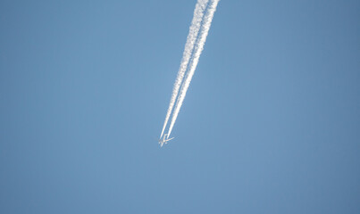 Passenger plane with a white trace of steam on a background of a blue sky without clouds. Air...