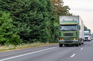 Old style cab over big rig semi truck transporting cargo in two dry van semi trailers running in...