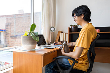 young man doing home office accompanied by a small dog